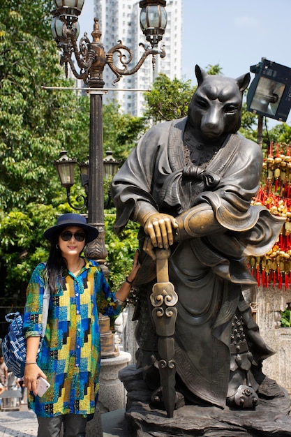 Reisende thailändische Frau, die am 9. September 2018 in Hongkong, China, für ein Foto mit zwölf chinesischen Sternzeichen Hundengelstatue im Wong-Tai-Sin-Tempel in Kowloon posiert