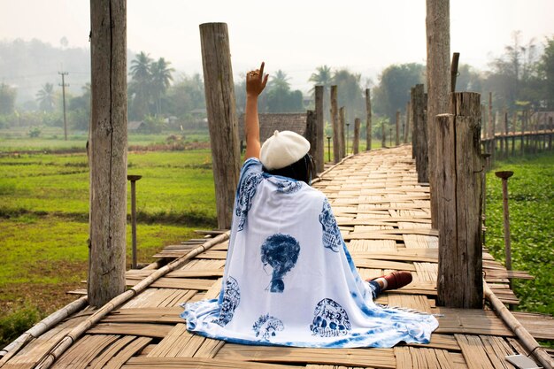 Reisende thailändische Frauen mit Indigo-Schal reisen besuchen und sitzen auf der Su Tong Pae Bambus-Holzbrücke, um ein Foto im Phu Sa Ma Tempel zu machen, während PM 25 Staubsituation in der Stadt Pai in Mae Hong Son Thailand