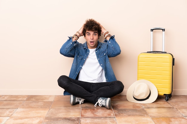 Reisender bemannen seinen Koffer, der auf dem Boden mit Überraschungsgesichtsausdruck sitzt