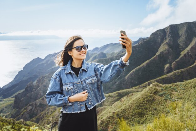 Reisender der jungen Frau, der ein selfie unter Verwendung eines Smartphone nimmt