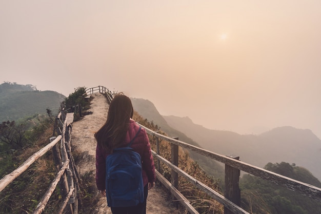 Reisender der jungen Frau, der Sonnenuntergang über dem Berg betrachtet