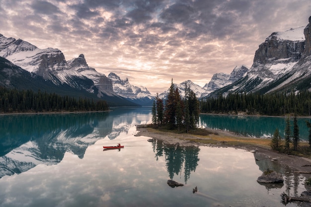 Reisender, der mit felsiger Gebirgsreflexion auf Maligne See in Geistinsel im Jaspis-Nationalpark canoeing ist