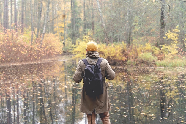 Reisender im Wald ein Mann mit Rucksack geht und fährt auf einer Spur in einem schönen Herbstwald ...