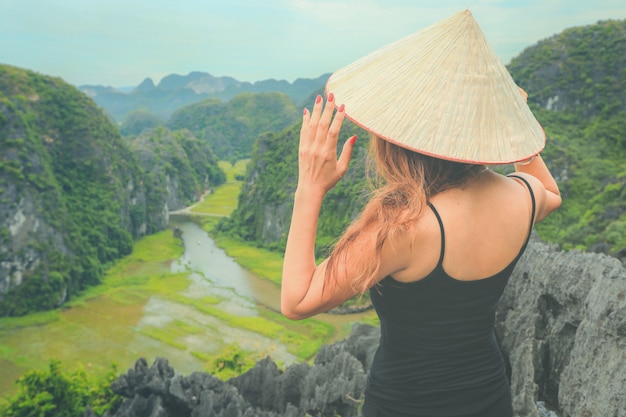 Foto reisender in vietnam. junge asiatische frau, die auf höchst-mua-höhle steht. provinz ninh binh, vietnam.