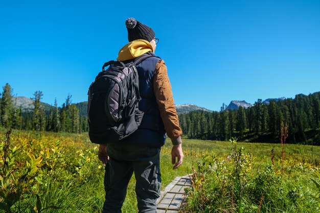 Reisender Mann mit Rucksack mit Blick auf die Berge. Rückansicht.