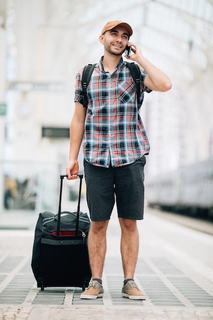 Reisender Mann telefoniert am Bahnhof phone