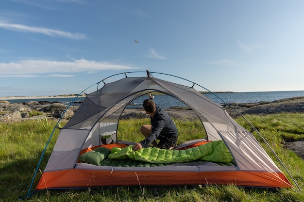 Reisender Mann Zelt am Strand aufstellen