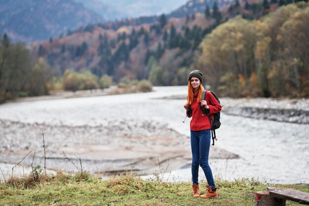 Reisender mit Rucksack auf Natur im Herbstwald und transparente Flussgebirgslandschaft