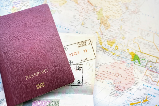 Reisepass auf einer Karte der Welt. Abreise- und Ankunftsstempel mit Visum. Reise-Reise-Ferien-Feiertagskonzept.