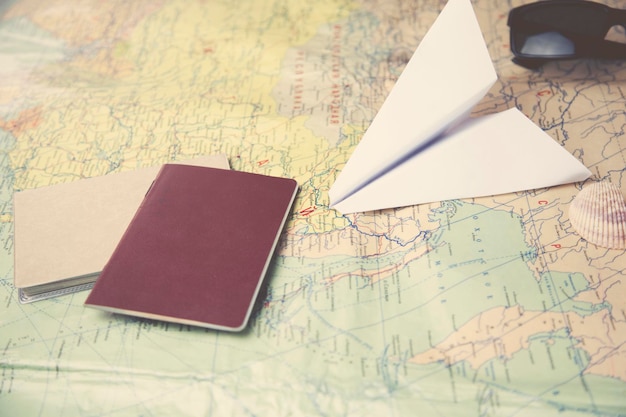 Reisepass, Sonnenbrille, Kamera, Kaffee und Flugzeug auf der Karte