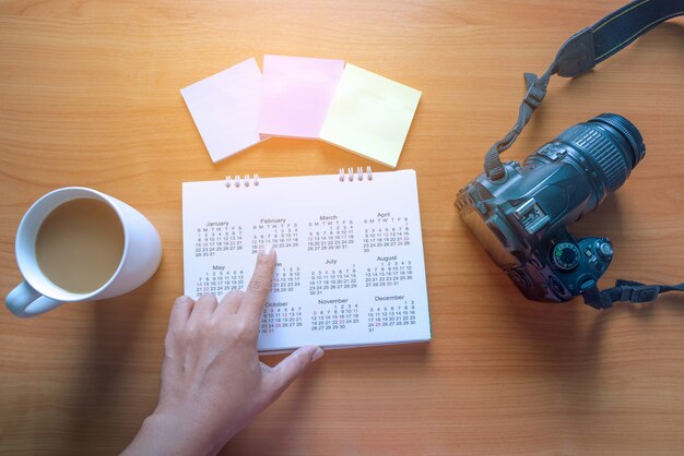 Reiseplanung im Kalender und Post-It für Notizen mit einer Tasse Kaffee auf einem Holztisch