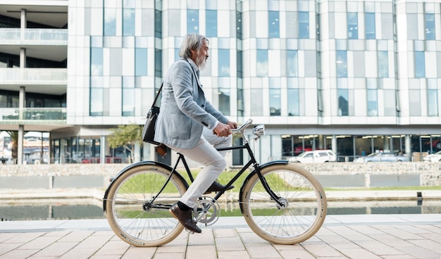 Reisestadt und asiatischer Geschäftsmann mit dem Fahrrad zur Arbeit in der Stadt für einen geringen CO2-Fußabdruck Nachhaltigkeitstransport und Senioren, die mit dem Fahrrad zum Arbeitsplatz fahren, um umweltfreundlich zu pendeln