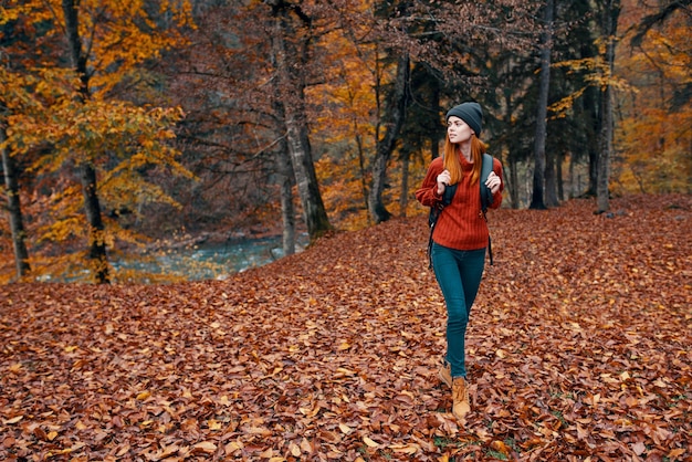 Reisetourismus und eine junge Frau mit einem Rucksack spazieren im Park in der Natur Landschaft hohe Bäume gefallene Blätter Fluss Hochqualitätsfoto