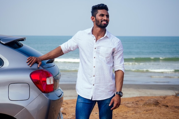 Reiseurlaub glücklicher indischer Mann im weißen Hemdkragen, der ein neues Auto kauft und den Schlüssel zeigt, im Auto am Strand Meer Indien Oktan Goa sitzend. Eine Reise zum Strand im Auto