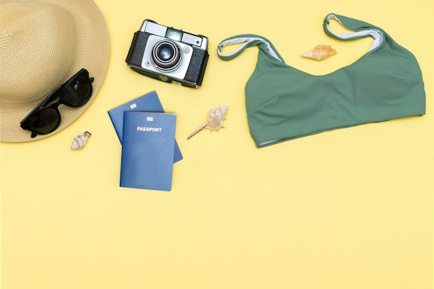 Reiseurlaub Sommer flach Zubehör Objekte Hut Pass Sonnenbrille Kleidung Badeanzug Kamera Muscheln auf gelbem Hintergrund mit Kopierraum Planungsreise Abenteuer