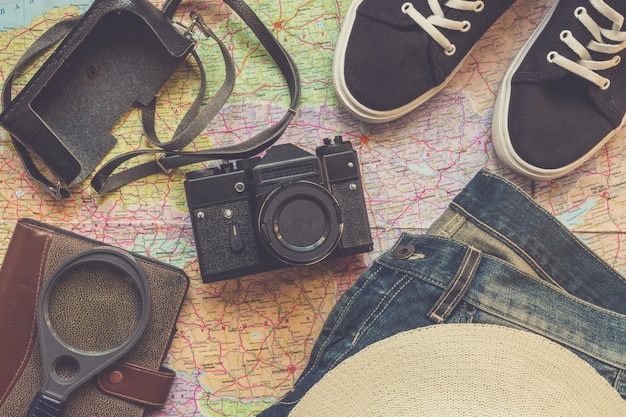 Foto reisezubehörkamera, strohhut, karte, schuhe, laptop, auf einem draufsichtplan des dunklen hintergrundes flach