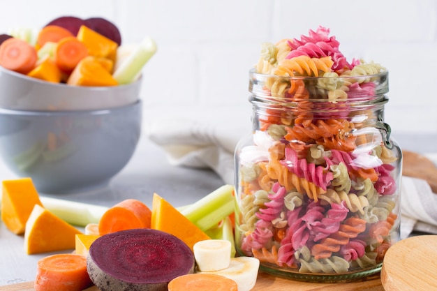 Reisfusilli trockene Nudeln aus Gemüse in einem Glas. Seine natürlichen Pflanzenfarben Sellerie, Rüben, Karotten, Kürbis, Pastinaken. Glutenfreies Konzept für gesunde Lebensmittel