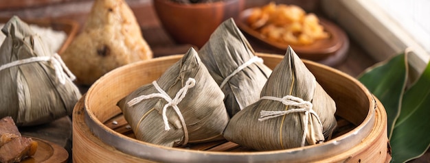 Reisknödel Chinesisches Zongzi-Essen in einem Dampfgarer auf Holztisch mit Fensterhintergrund aus rotem Backstein zu Hause für das Konzept des Drachenbootfestivals aus nächster Nähe