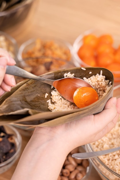 Reisknödel Zongzi, der chinesische Reisknödel Zongzi auf dem Tisch zu Hause für die Feier des Drachenbootfestes in der Nähe des Lebensstils einwickelt