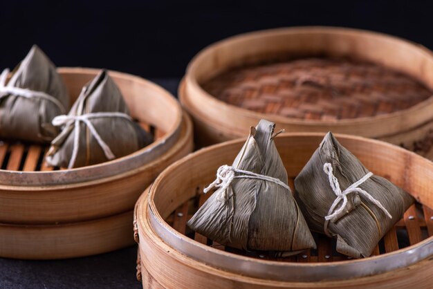 Reisknödel Zongzi Essen Junge asiatische Frau isst chinesisches traditionelles Essen auf Holztisch zu Hause für die Feier des Drachenbootfestes aus nächster Nähe