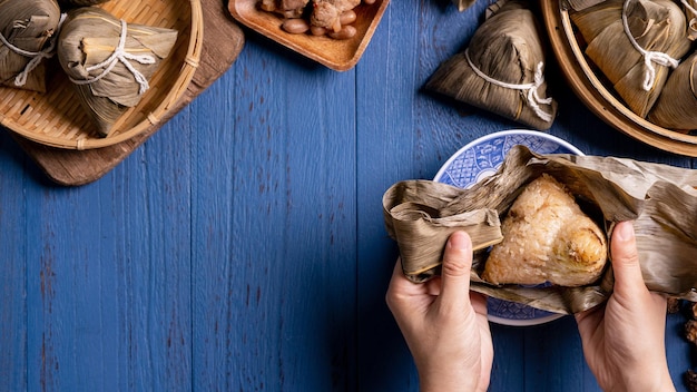 Reisknödel Zongzi Traditionelles chinesisches Essen auf blauem Holzhintergrund des Drachenbootfestivals Duanwu Festival Draufsicht flach lag Designkonzept