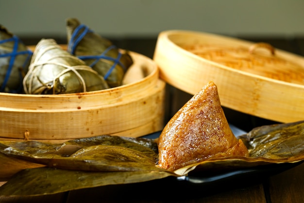 Foto reisknödel zongzi und bambusdämpfer auf holztisch