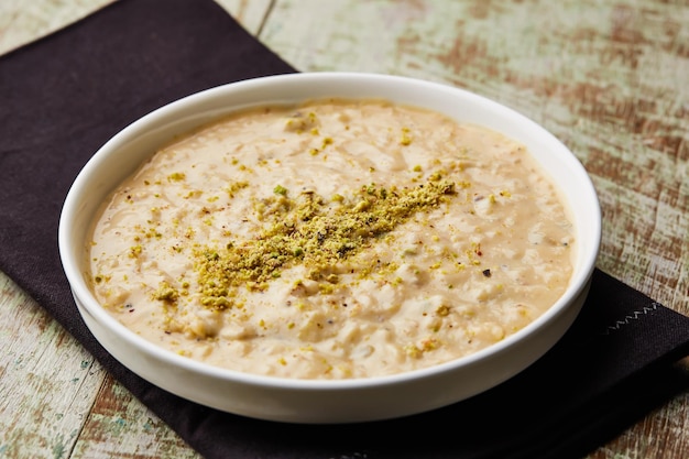 Foto reispuddingbrei kheer khir oder firini süßes topping mit pistazien serviert in einem gericht isoliert auf der tischplatte ansicht auf arabische dessert-lebensmittel