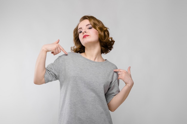 Reizend junges Mädchen in einem grauen T-Shirt auf einem Grau