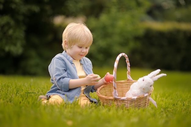 Reizend kleiner Junge, der im Frühjahr für Park Ostereies am Ostertag jagt.