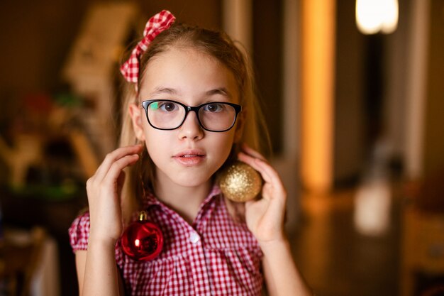 Reizend kleines Mädchen in der weißen und roten Kleidung mit Weihnachtsdekoration