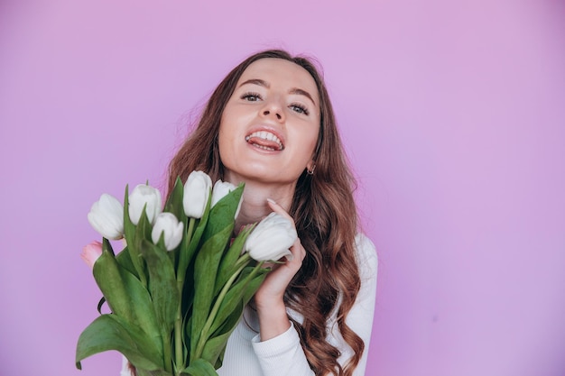 Reizende Blondine, die Blumenstrauß für Frühlingsferien erhält. Festliches Konzept