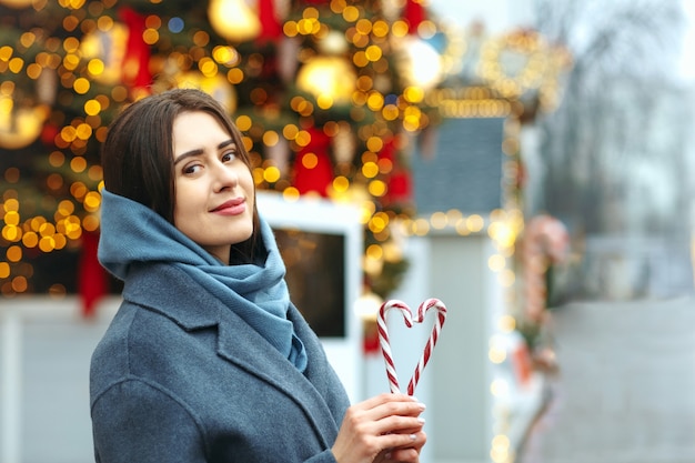 Reizende Brunettefrau, die Bonbons in einer Herzform hält. Platz für Text