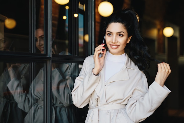 Reizende Brunettefrau mit dem gewellten Haar gebunden im Pferdeschwanz, der das schöne blasse Gesicht elegant schaut hat