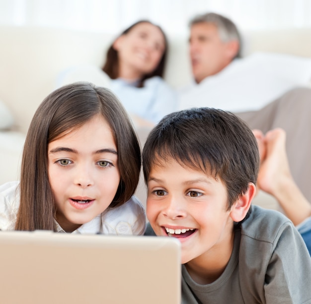 Reizende Kinder, die zu Hause einen Film auf ihrem Laptop aufpassen