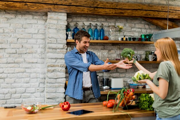 Reizende nette junge Paare, die zusammen Abendessen kochen