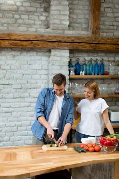 Reizende nette Paare, die zusammen Abendessen kochen und Spaß an der rustikalen Küche haben