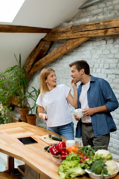 Reizende nette Paare, die zusammen Abendessen kochen und Spaß an der rustikalen Küche haben