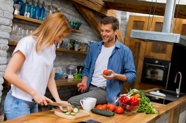 Reizende nette Paare, die zusammen Abendessen kochen und Spaß an der rustikalen Küche haben