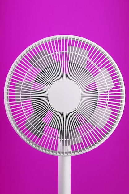 La rejilla y las aspas del ventilador eléctrico son de color blanco sobre fondo rosa.