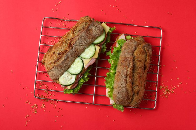 Rejilla para hornear con sándwiches ciabatta sobre fondo rojo.