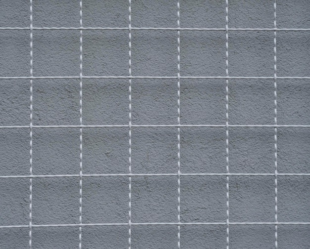 Una rejilla metálica y una pared gris detrás
