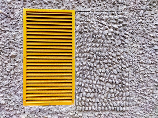 Foto una rejilla de ventilación amarilla en una pared gris