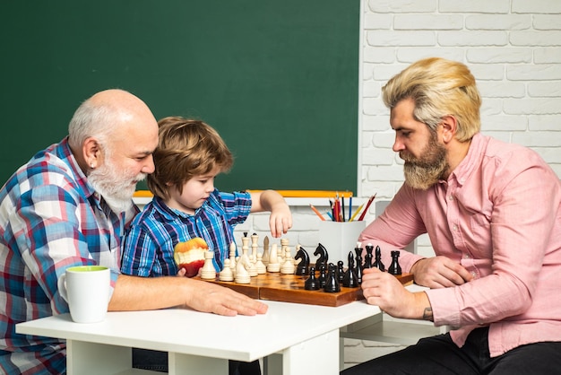 Relação familiar entre avô pai e filho avô ensinando menino de escola jogando xadrez filhote