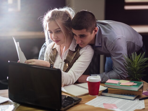 Relación amorosa. asunto de oficina. romance en el lugar de trabajo. intimidad de los compañeros de trabajo. hombre inclinado sobre una mujer que trabaja en el escritorio.