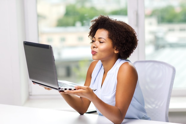 relación distante, comunicación en línea y concepto de amor - feliz joven afroamericana enviando un beso a la computadora portátil