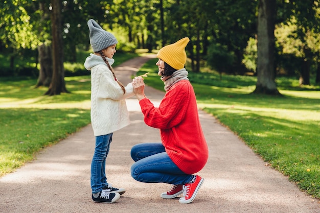 Relación de personas concepto de paternidad e infancia Hermosa madre juega con su pequeña hija en el parque da hoja amarilla tiene emociones sinceras y siente o ama a su encantadora hija