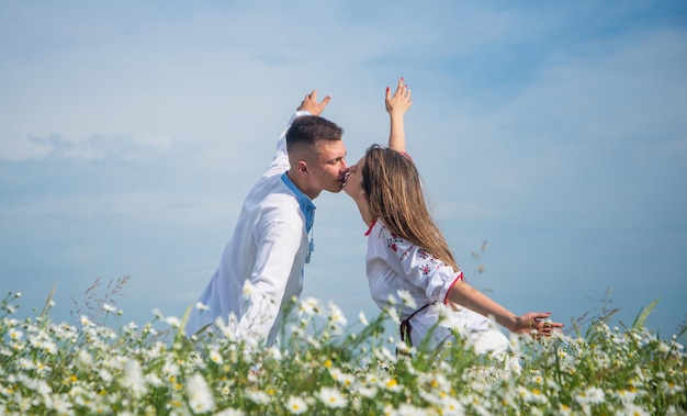 Relacionamento romântico jovem e livre lindo casal apaixonado homem e mulher no campo de flores de camomila férias de verão família feliz entre flores primavera natureza beleza amor e romance