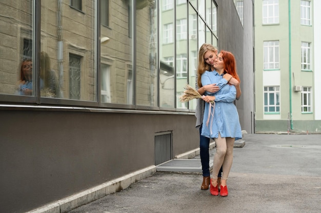 Relacionamentos homossexuais Casal feliz de lésbicas com flores secas A menina abraça gentilmente a namorada ruiva por trás Feche um par de mãos LGBT