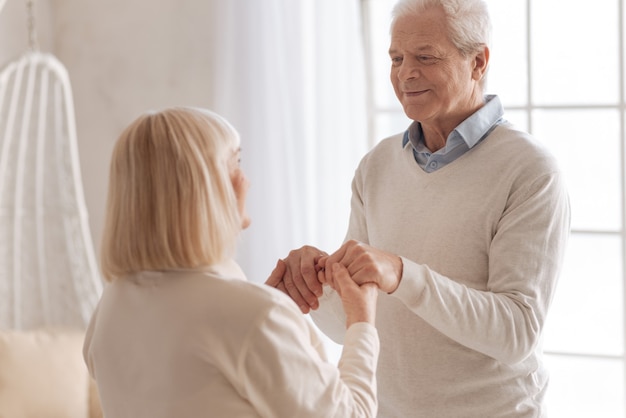 Relacionamentos longos. homem idoso e simpático, de mãos dadas com a esposa, sorrindo enquanto está com ela