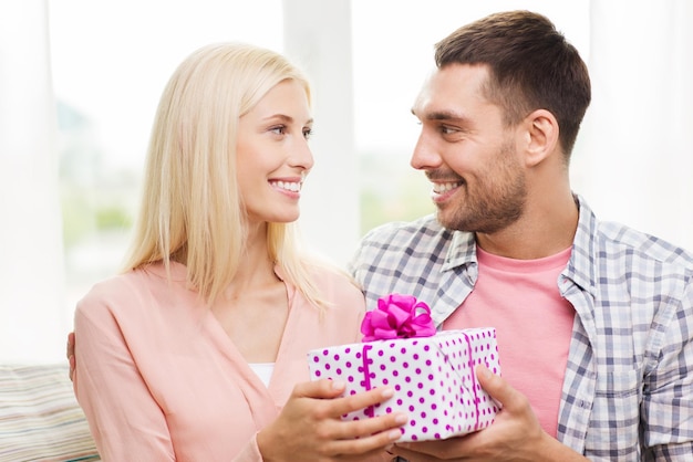 relaciones, amor, gente, concepto de cumpleaños y vacaciones - hombre feliz dando caja de regalo a la mujer en casa